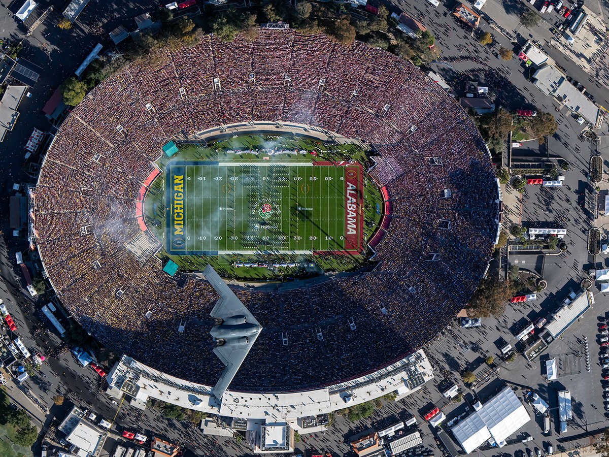 Aerial view of a B-2 Stealth Bomber flying over the 2024 Rose Bowl Game at the conclusion of the National Anthem, showcasing its sleek design and advanced technology to the crowd below.