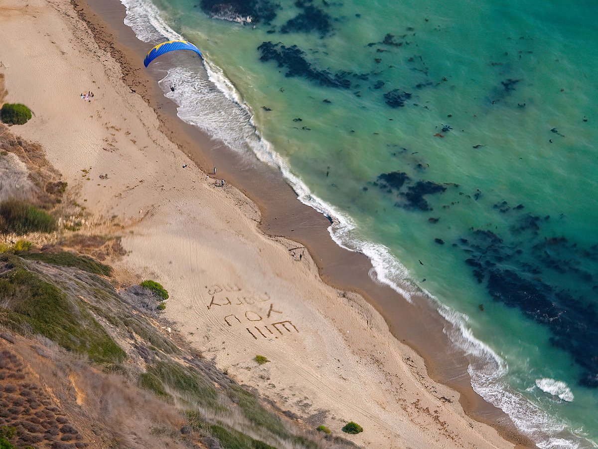 Aerial photograph of a glider above a wedding proposal written in the sand at the beach in Palos Verdes, California
