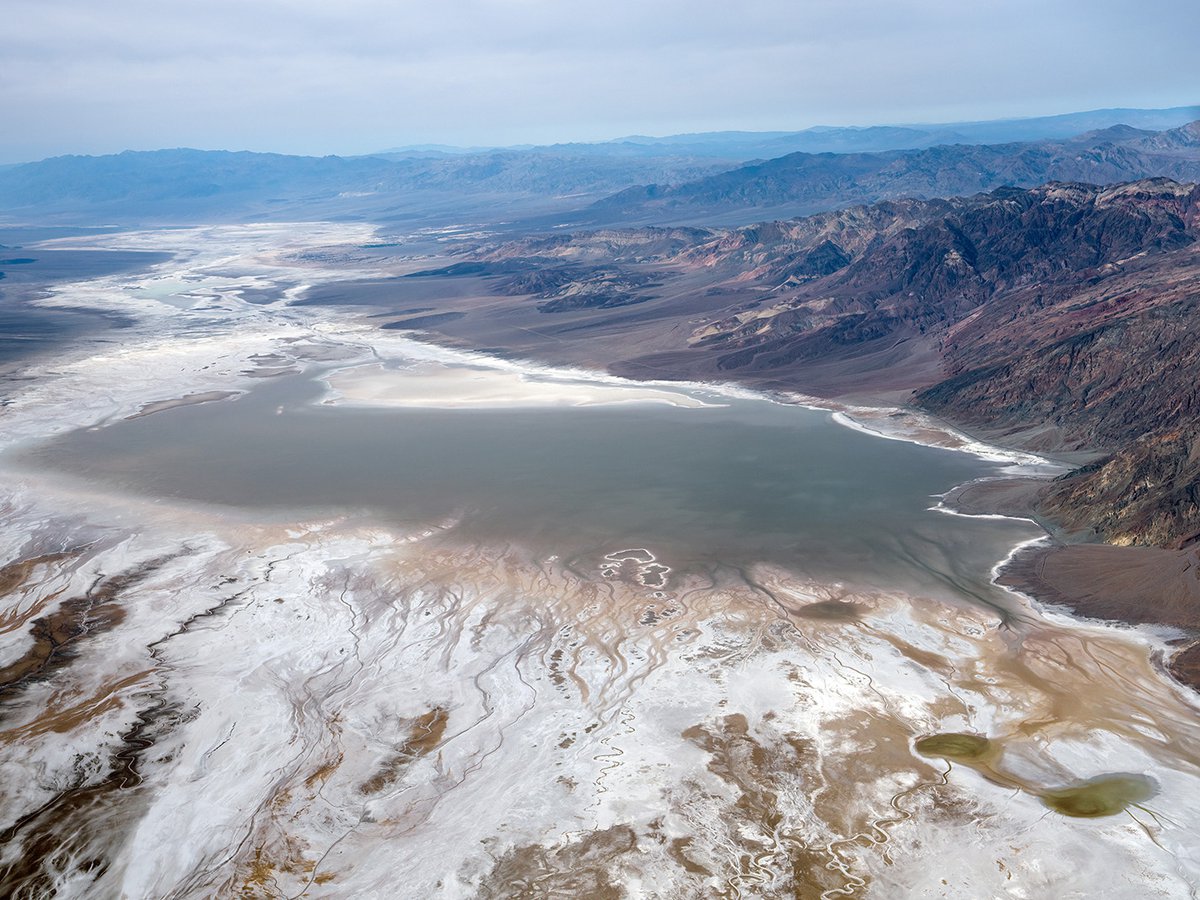 Aerial photograph capturing the mesmerizing beauty of Lake Manly in Death Valley, California, as it recedes and forms intricate irregular geometrics shapes amidst the vast expanse of Badwater Basin's iconic salt flats.